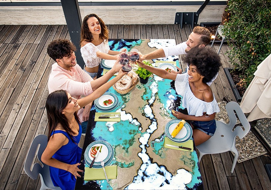 Amici brindano a cena su un tavolo d'arte in terrazza.