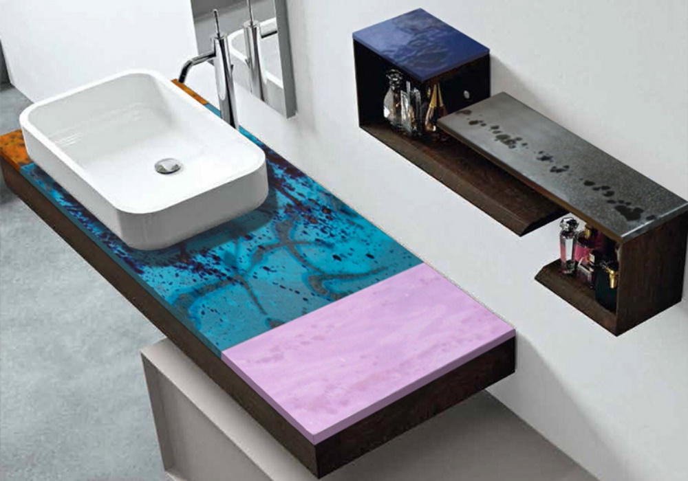 Lavabo rettangolare bianco su mobile bagno moderno con piano blu-turchese e rosa, mensole a muro con profumi.