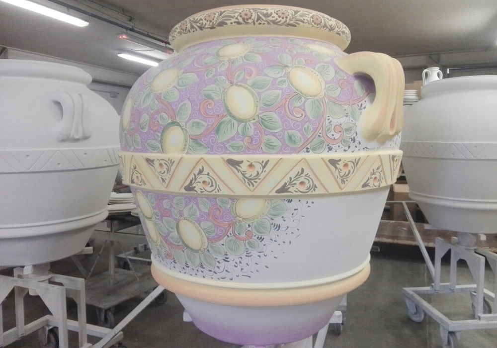 Vaso in ceramica decorato a mano con motivi floreali e limoni, in un laboratorio artigianale.