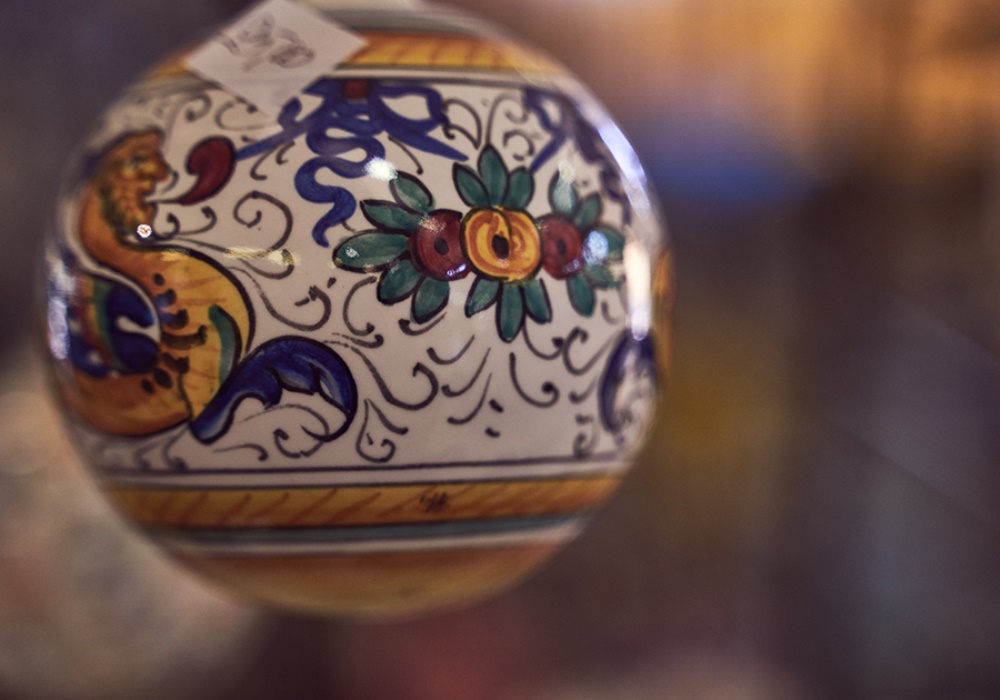 Palla di ceramica decorata a mano con motivi floreali e uccelli, colori vivaci, stile tradizionale siciliano.