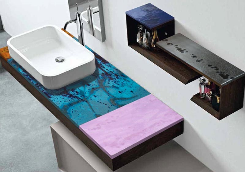 Lavabo moderno con piano d'appoggio artistico blu e rosa, mensole a muro con profumi.