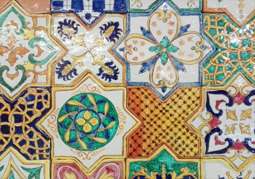 Piastrelle in ceramica dipinte a mano con motivi geometrici e floreali in stile mediterraneo.
