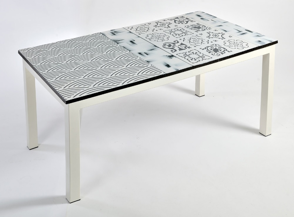 Tavolo moderno con piano decorato a motivi geometrici e floreali in bianco e nero, gambe bianche.