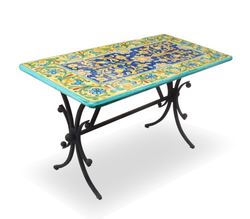 Tavolo rettangolare in ferro battuto con piano in ceramica dipinta a mano, motivi floreali gialli e blu.