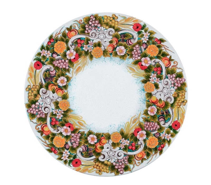 Piatto decorativo rotondo con motivo floreale e fruttato, foglie e spighe di grano su sfondo bianco.
