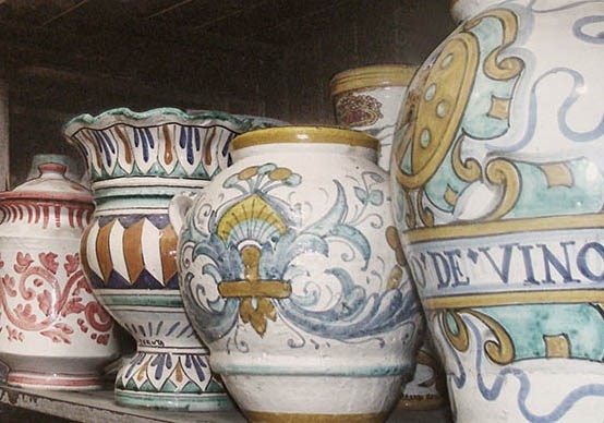 Vasi in ceramica dipinti a mano con motivi tradizionali e colori vivaci, esposti su uno scaffale.