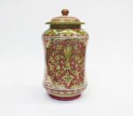 Vaso in ceramica dipinto a mano, decorato con motivi floreali verdi e rossi su sfondo bianco.