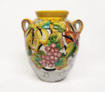 Vaso in ceramica dipinto a mano con frutta e foglie, stile mediterraneo, sfondo bianco.